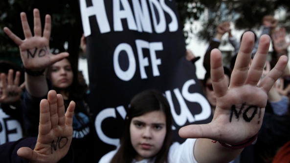Protesters raise their open palms showing the word "No" during an anti-bailout rally in Nicosia